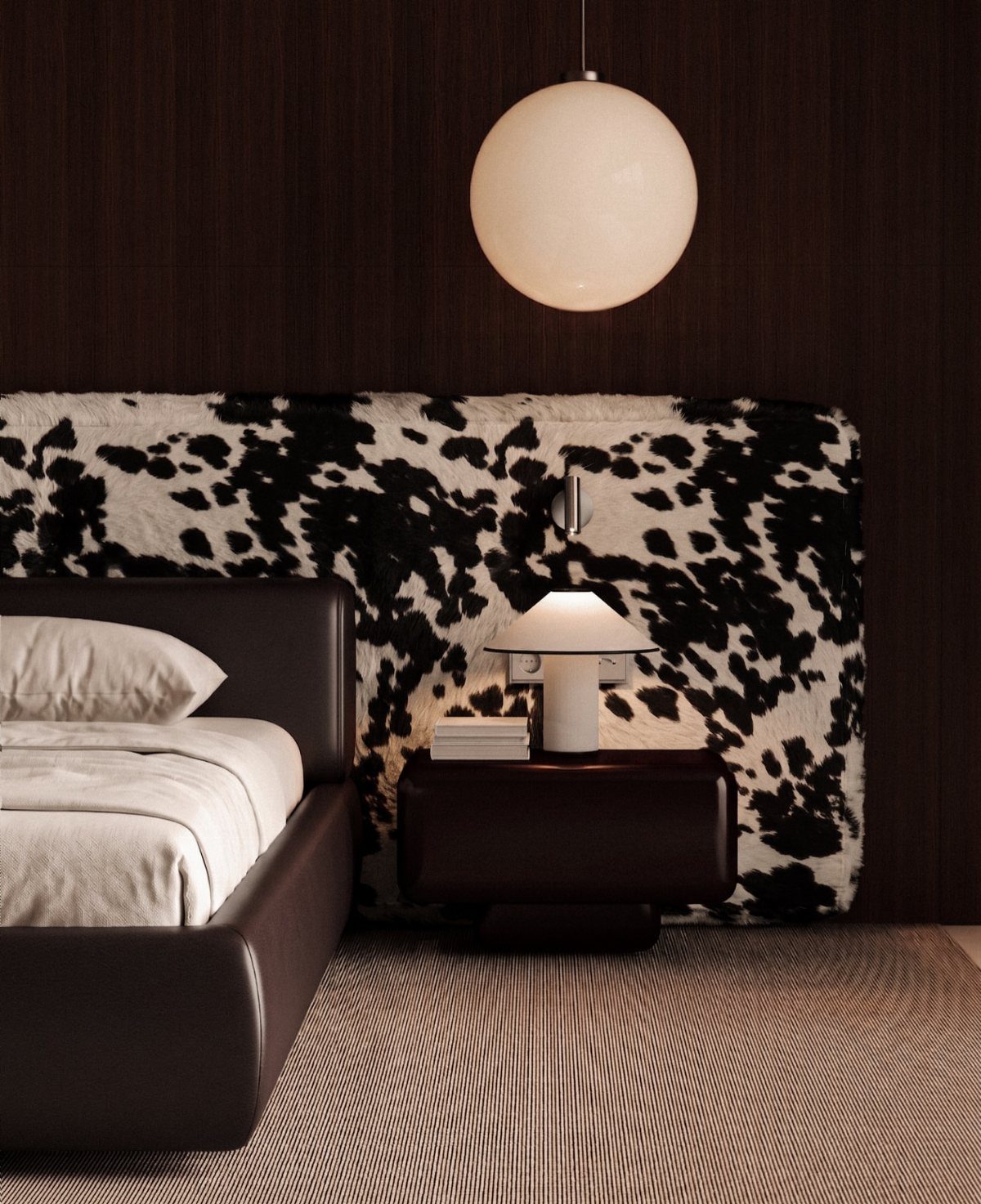Cow print headboard behind a brown bed with a white globe pendant light.