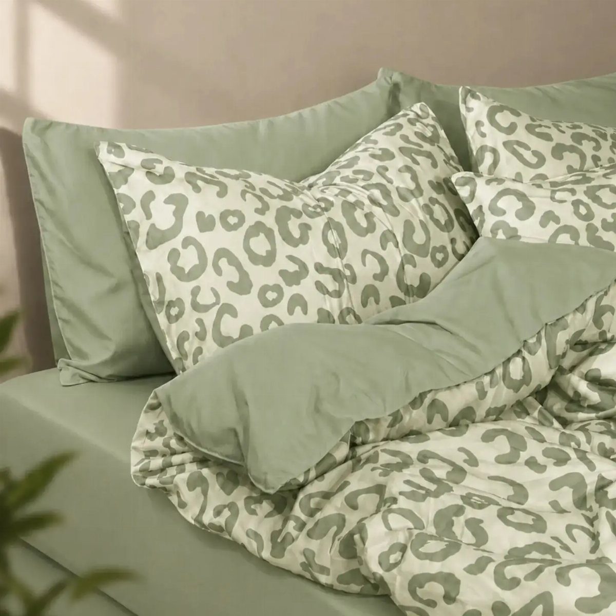 Leopard print bedding in light green and white on a neatly made bed.