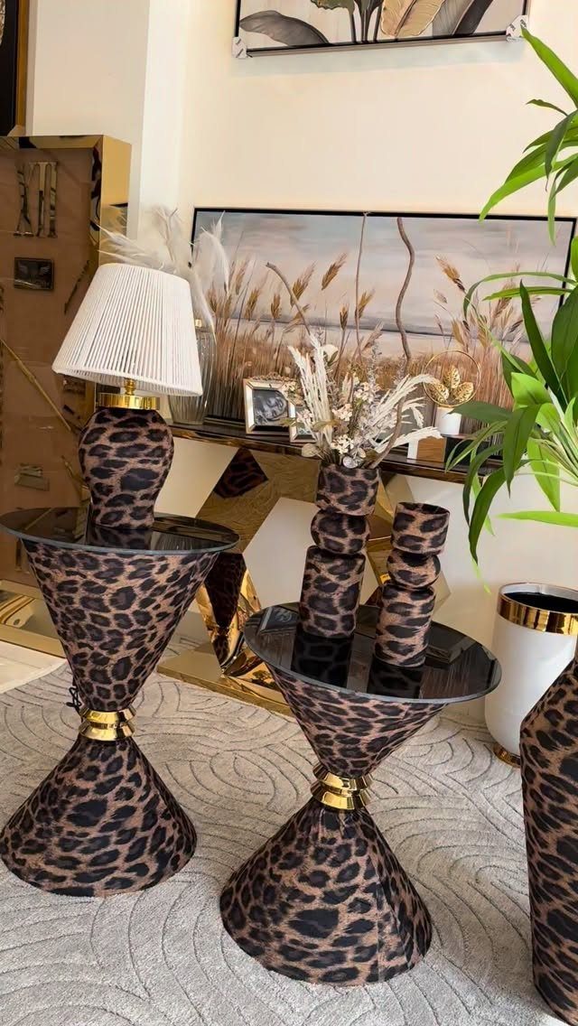 Leopard print hourglass side tables with a white lamp and dried grass decor.