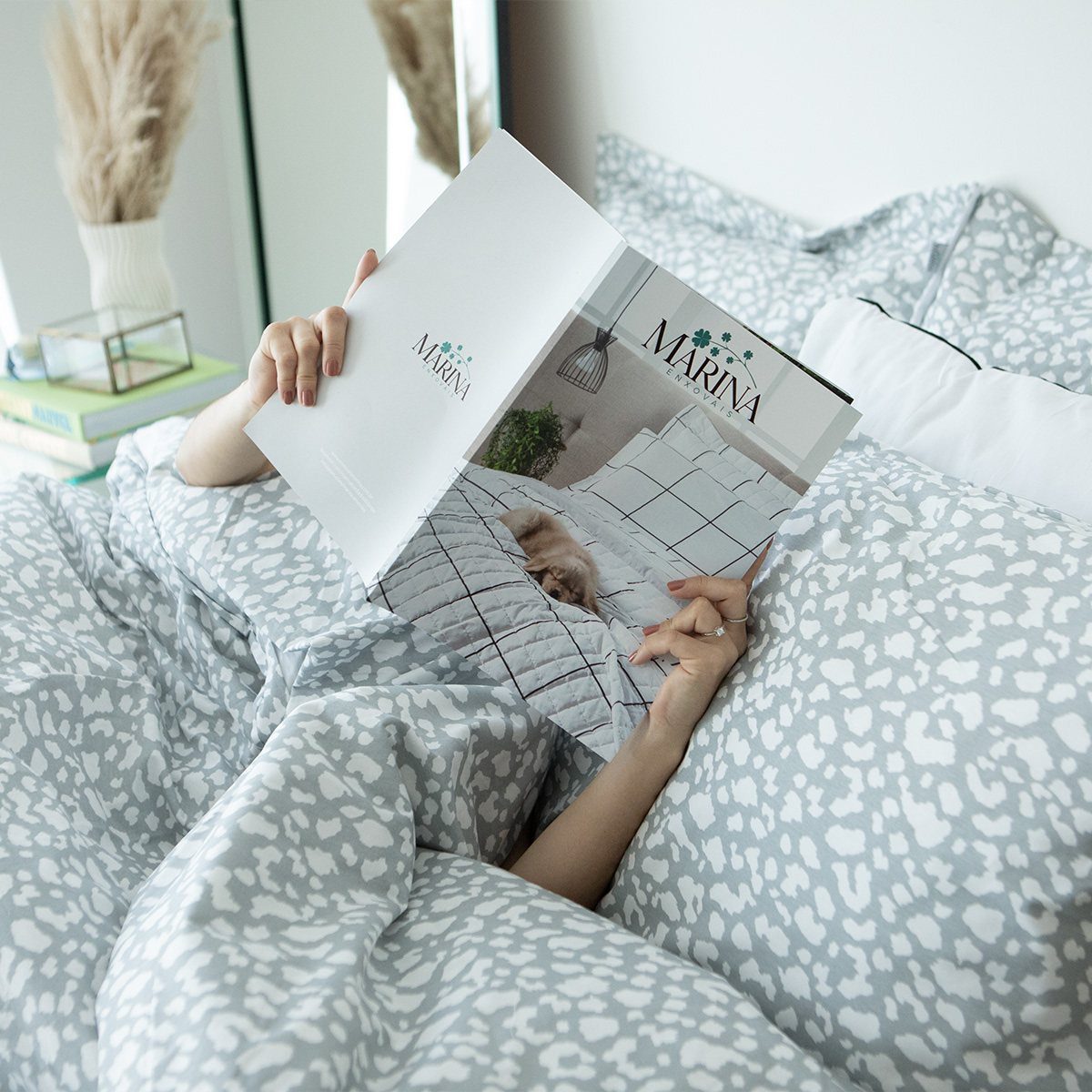 Gray and white leopard print bedding with a person reading a magazine