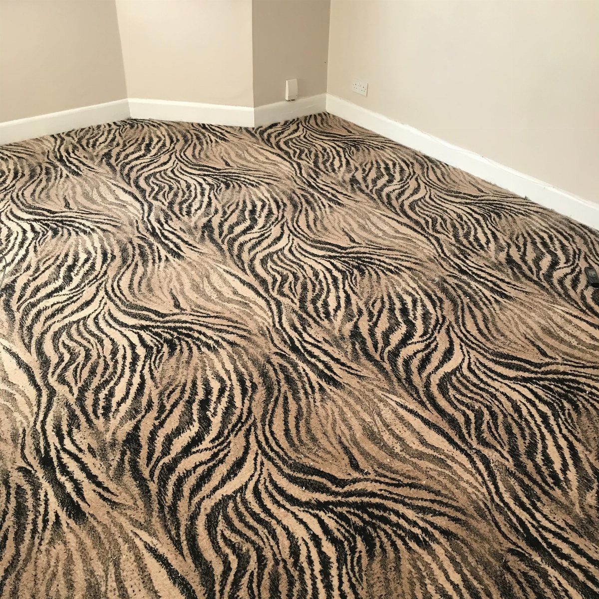 Tiger print carpet covering the floor of a room with beige walls.
