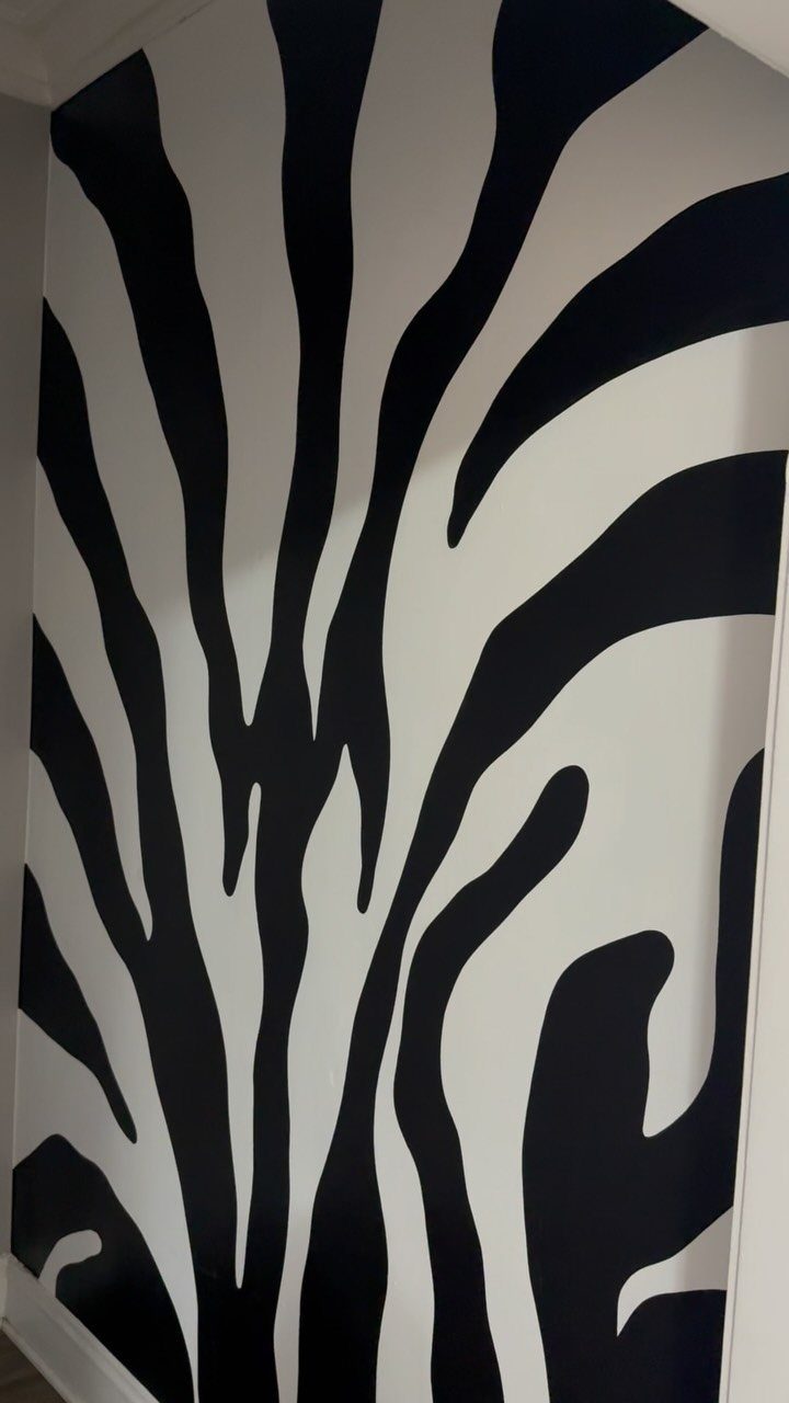 Zebra print accent wall with bold black and white flowing stripes.