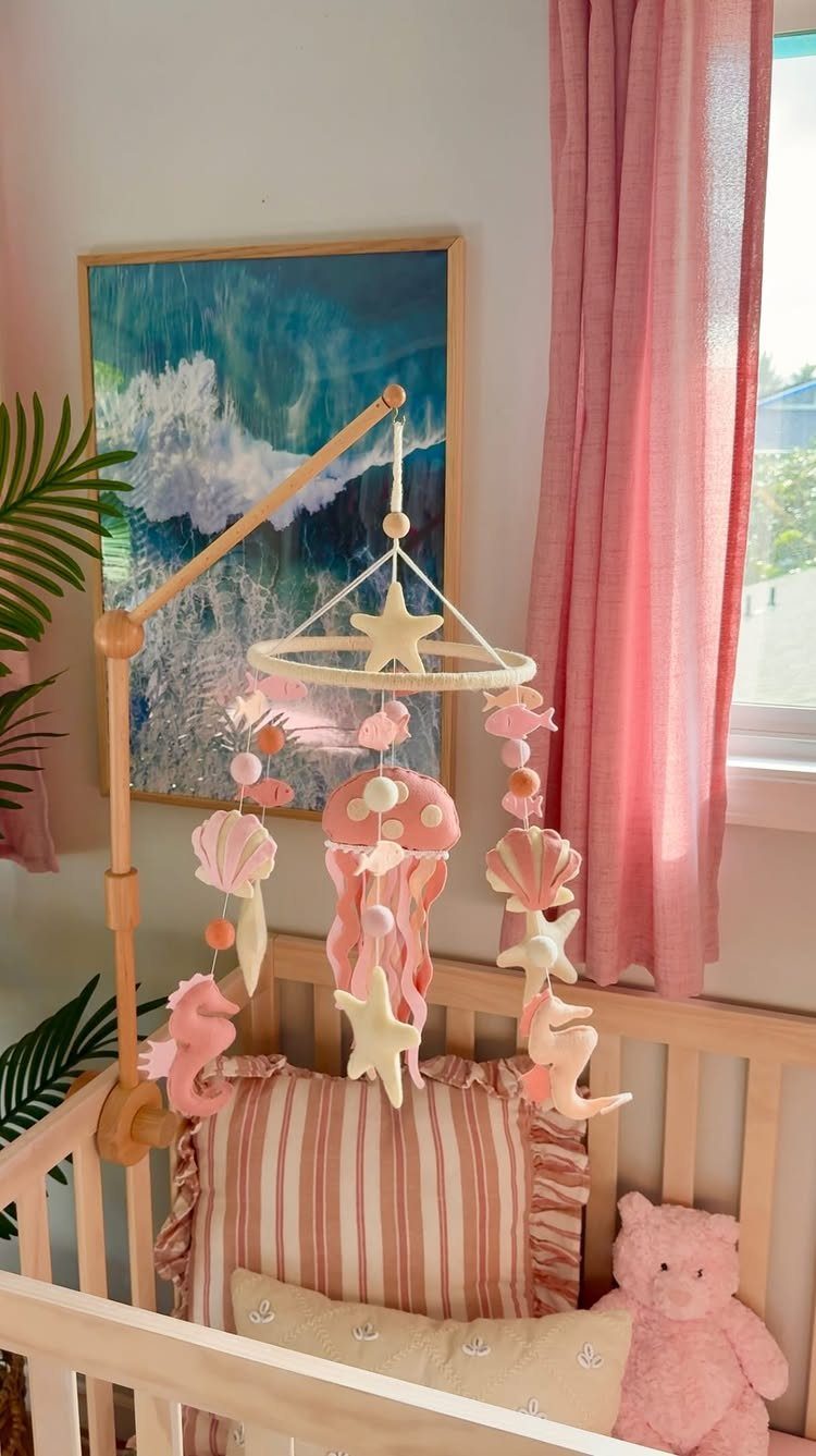 Ocean themed baby crib with pink accents and a seashell mobile