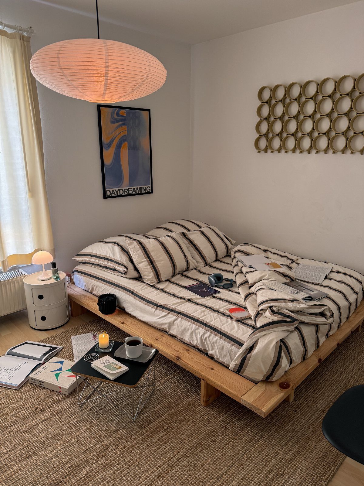 Low wooden platform bed with striped bedding in a minimalist white bedroom