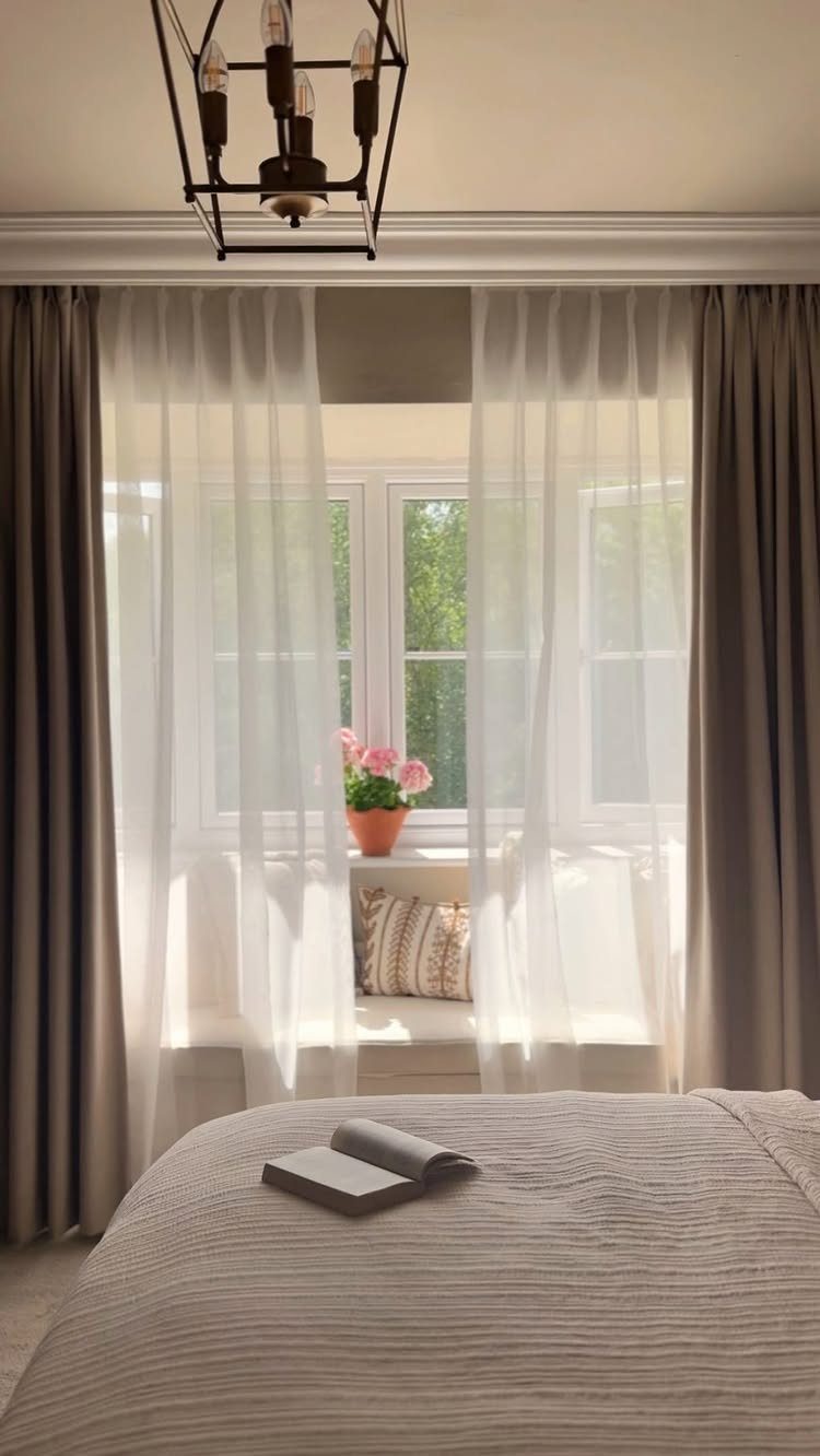 Sheer white and taupe curtains framing a window with a cozy window seat.