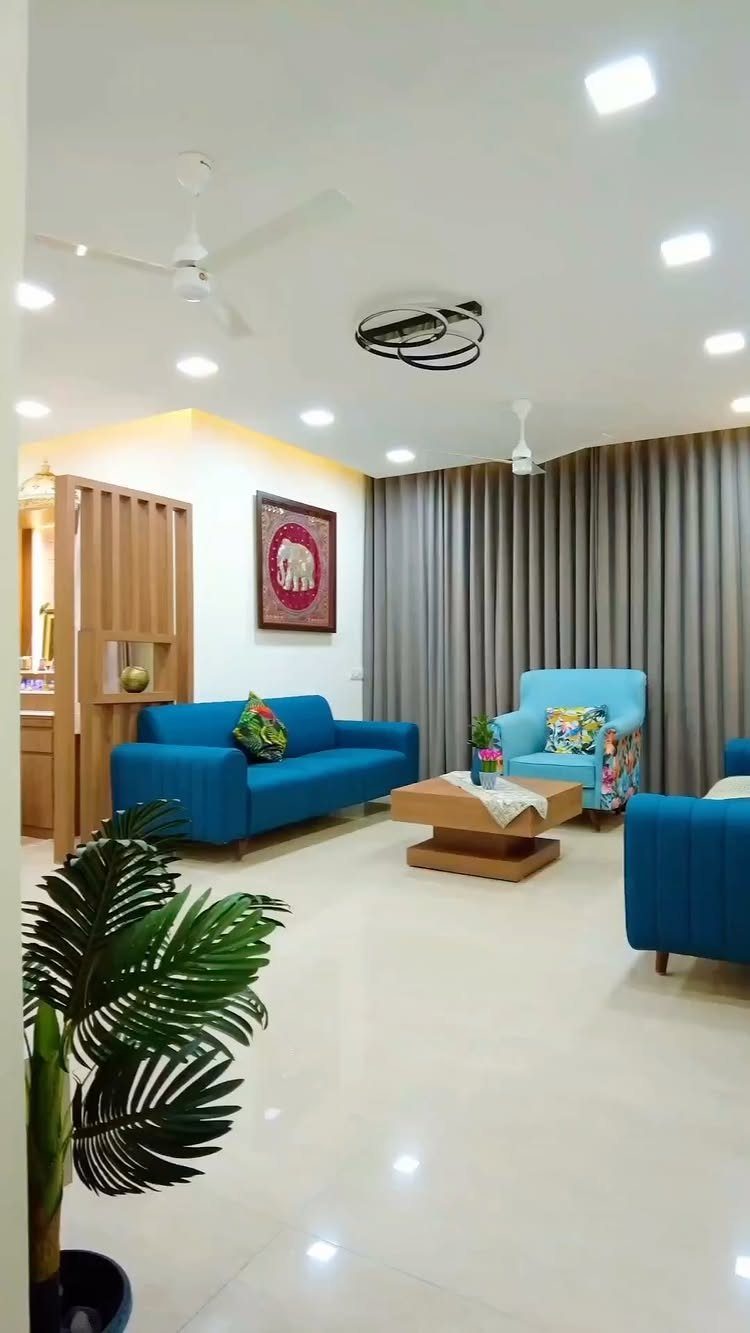 Blue sofas and armchair in a bright living room with grey curtains.
