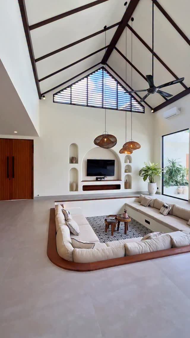 Sunken living room with a large beige sectional sofa and vaulted ceiling beams.