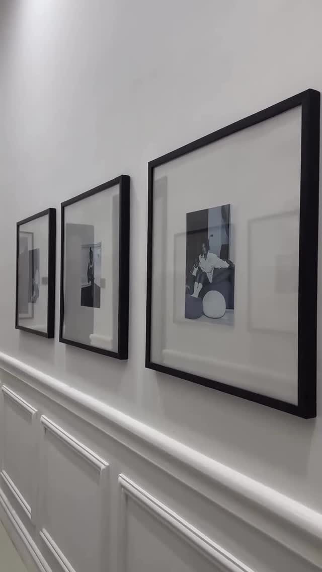 Three black-framed art prints hanging on a white wall with decorative panelling.