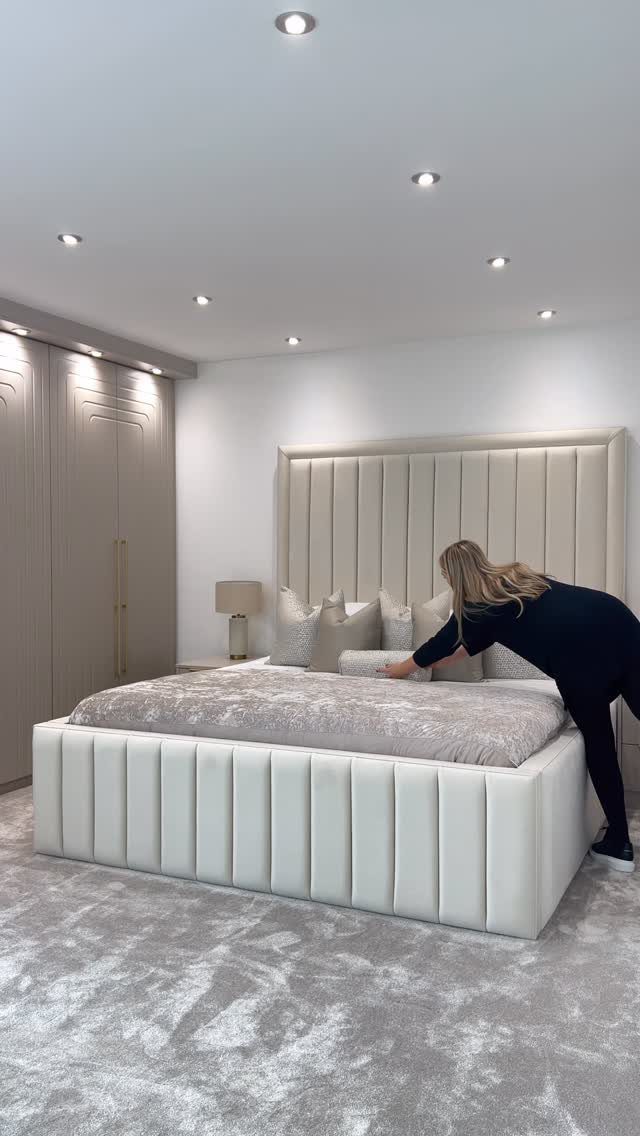 Tall cream upholstered channeled headboard on a bed in a modern bedroom.