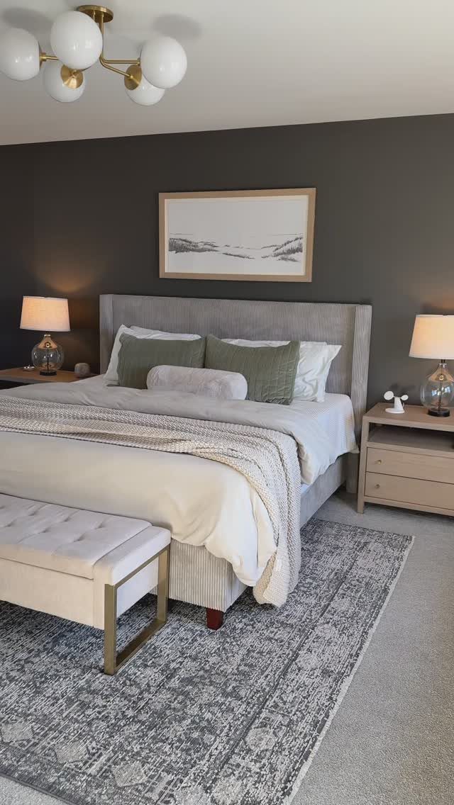 Bedroom with a dark charcoal accent wall, grey bed, and neutral decor.