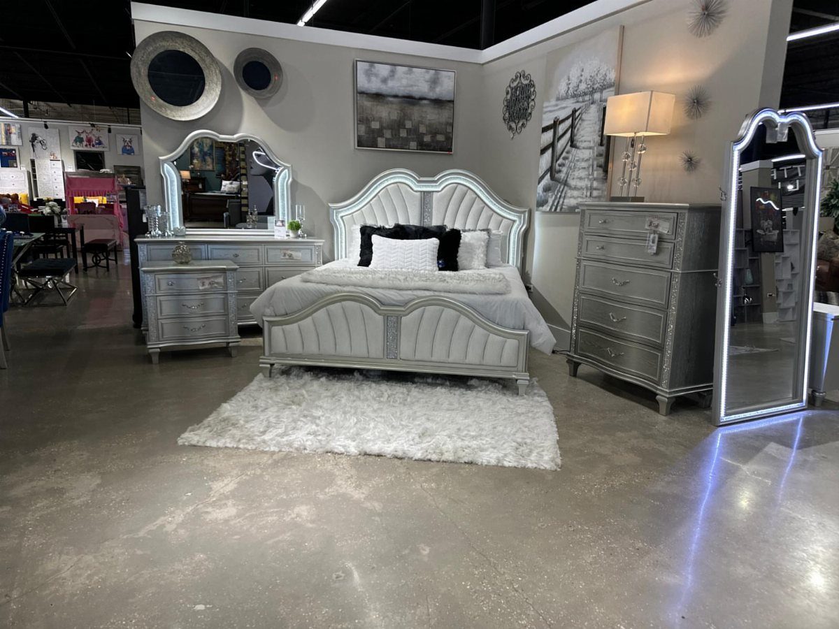 Silver metallic bedroom furniture set with a tufted bed and white fluffy rug.