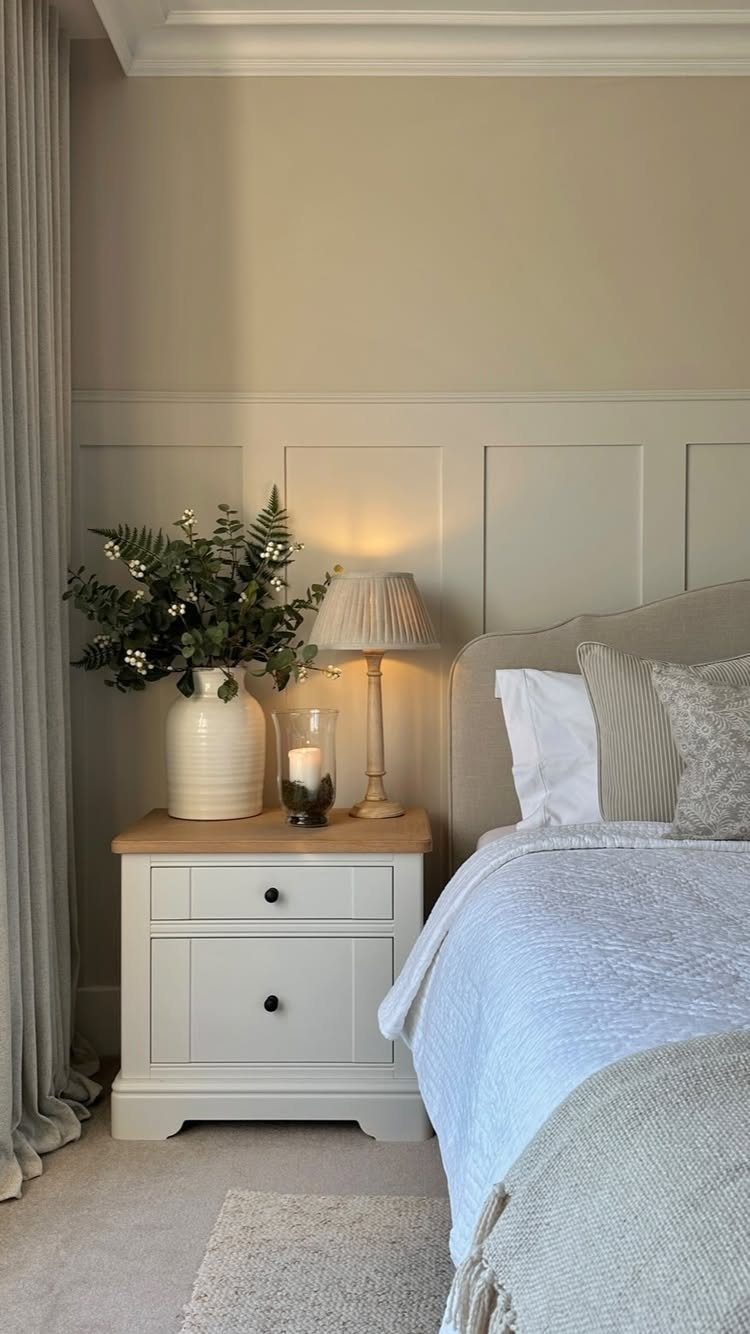 Bedside lamp with pleated shade on a white nightstand next to a bed