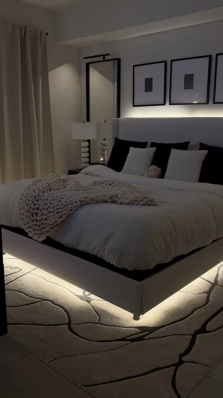 White bed with cozy sheets and a chunky knit throw on a patterned rug.