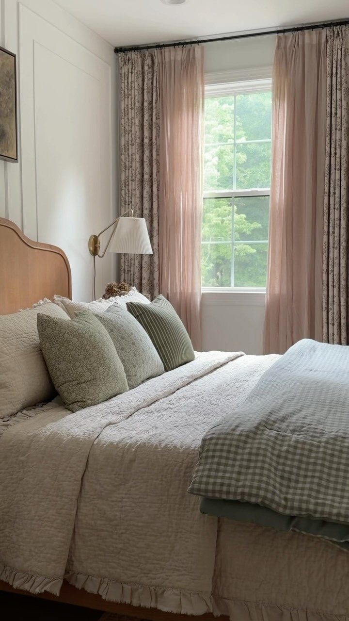 Layered pink and patterned curtains framing a window in a cozy bedroom.