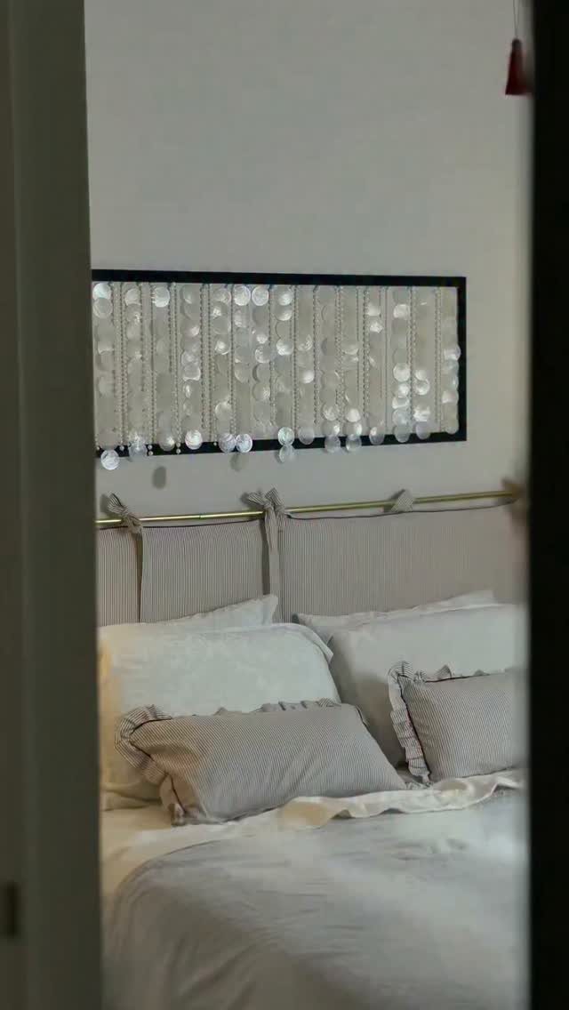 Bed with white linens and a DIY fabric panel headboard on a gold rod