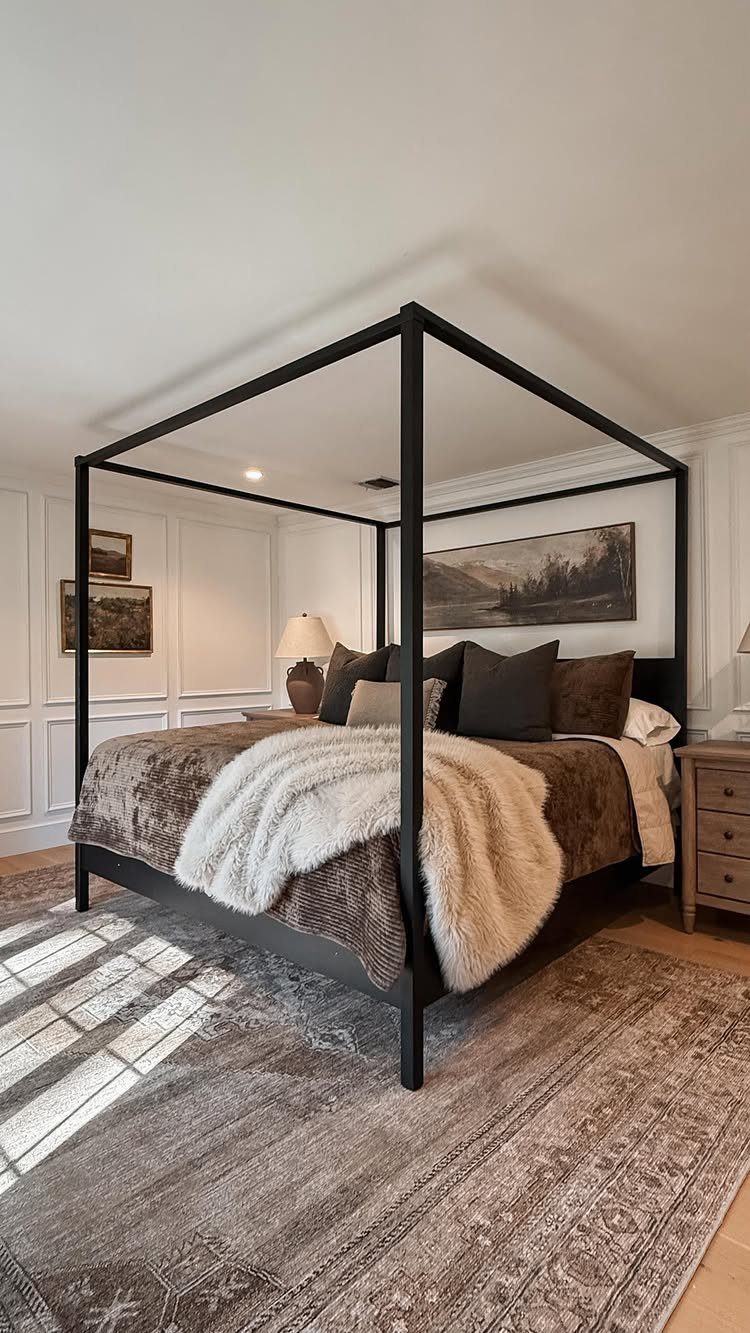 Large patterned area rug under a black four-poster bed in a bedroom