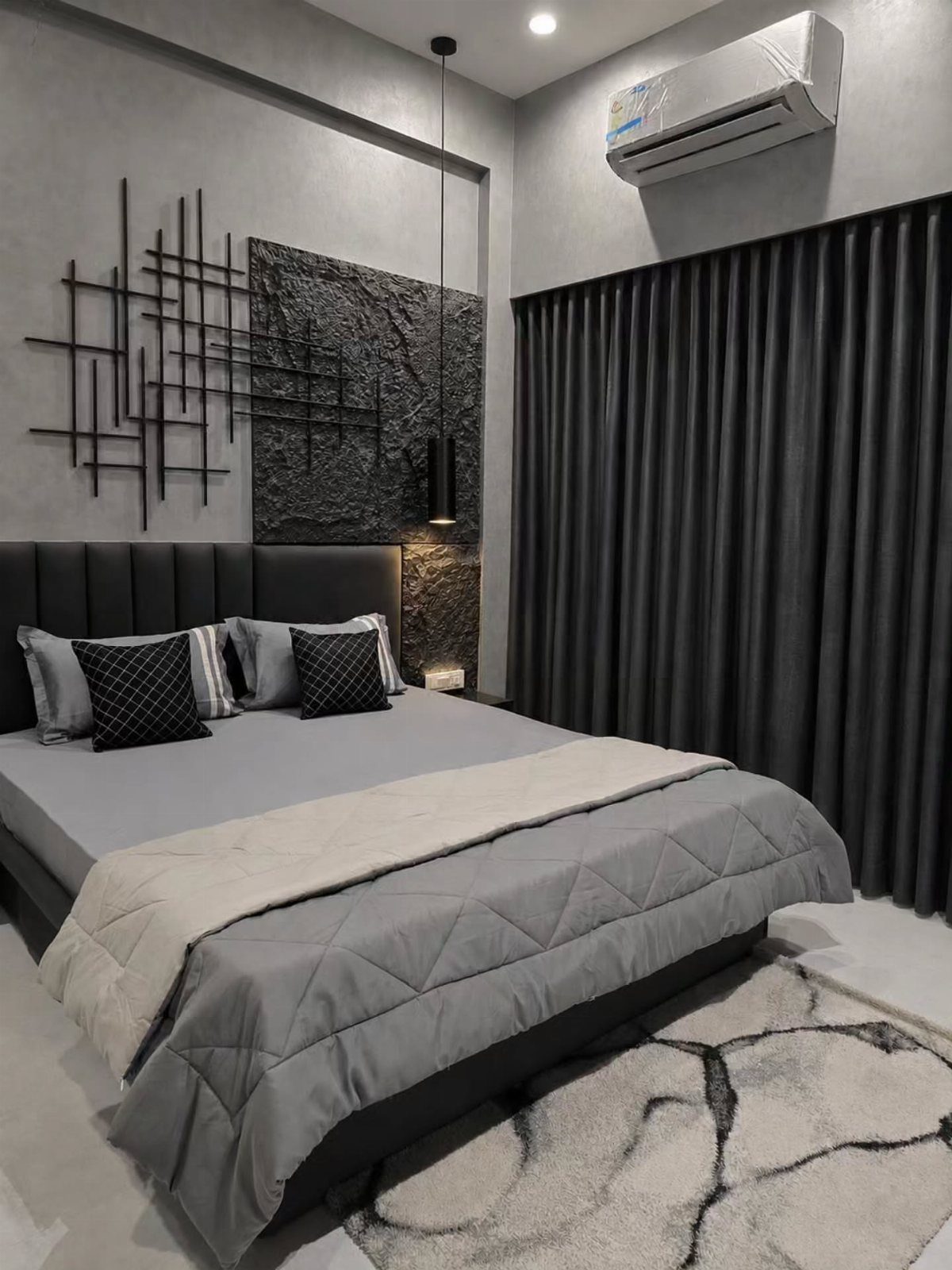 Charcoal gray bedroom with a quilted gray bed, dark curtains, and abstract wall art.