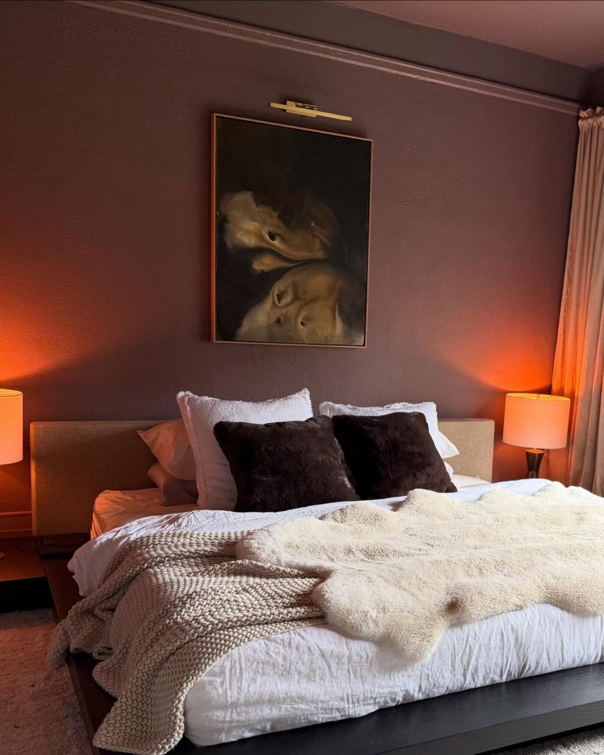 Mauve purple bedroom walls with a bed, white linens, and a framed painting.