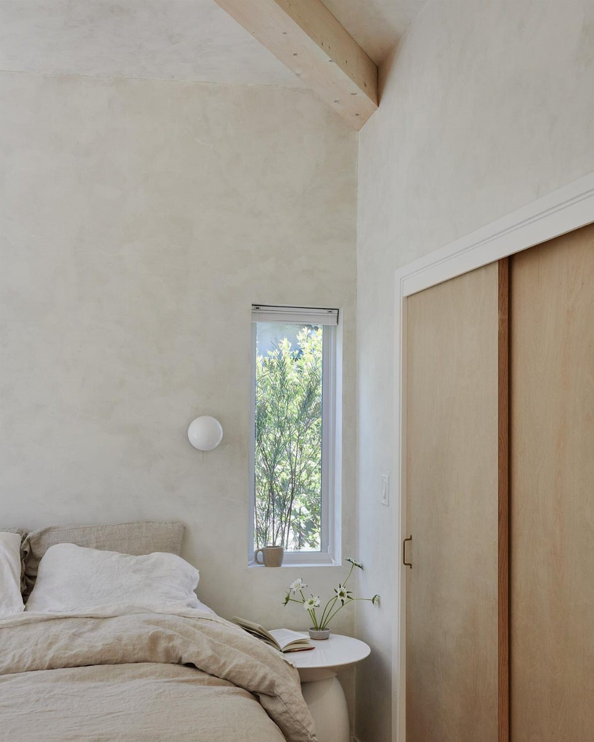 Textured off-white plaster walls in a minimalist bedroom with light wood accents.