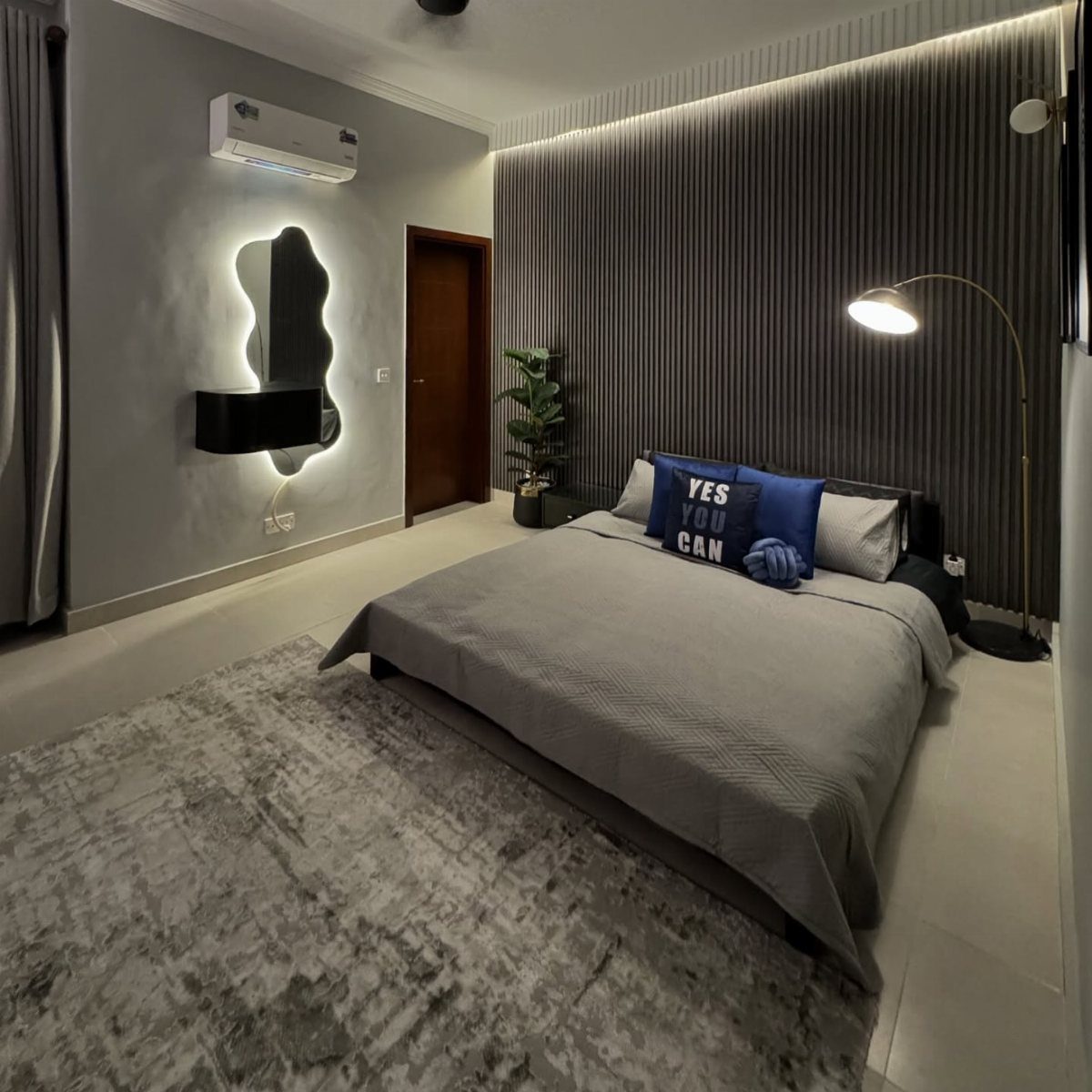 Modern bedroom with a dark grey striped accent wall and grey bedding.