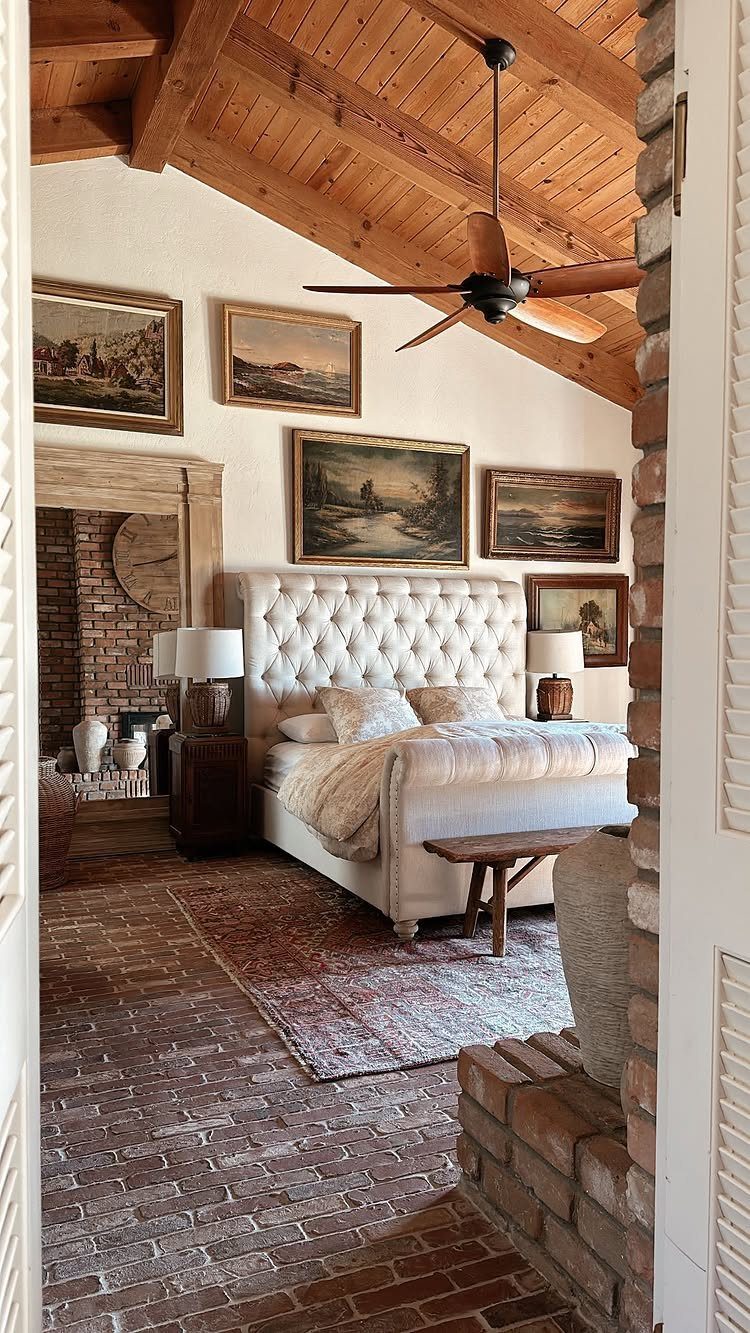 Tufted white bed in a rustic room with framed art on the wall.