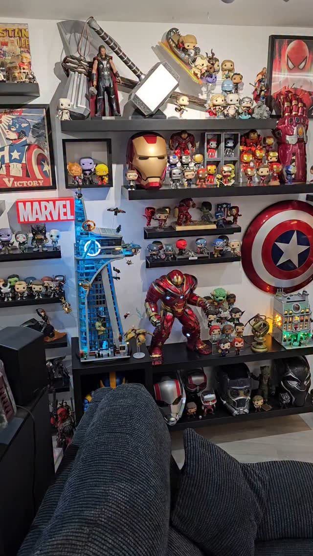 Marvel collectibles and action figures displayed on black shelves in a room.