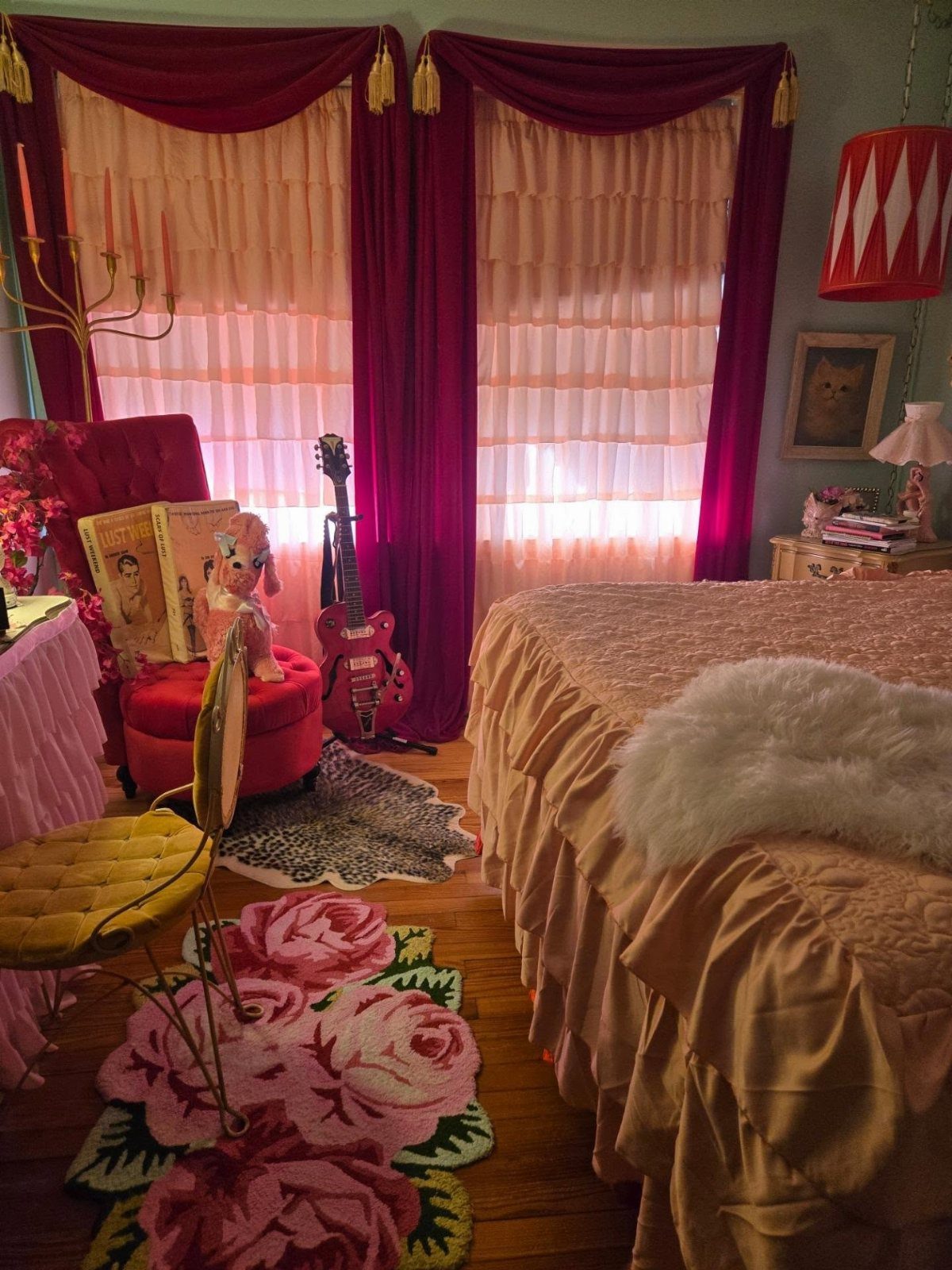 Bedroom with red velvet curtains, rose-patterned rug, and peach ruffled bedding.