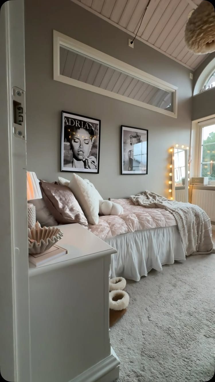 Bed with blush pink bedding and white pillows in a grey bedroom.