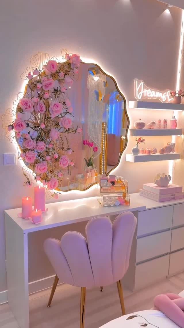 White vanity desk with a shell-shaped pink chair and rose-decorated glowing mirror.