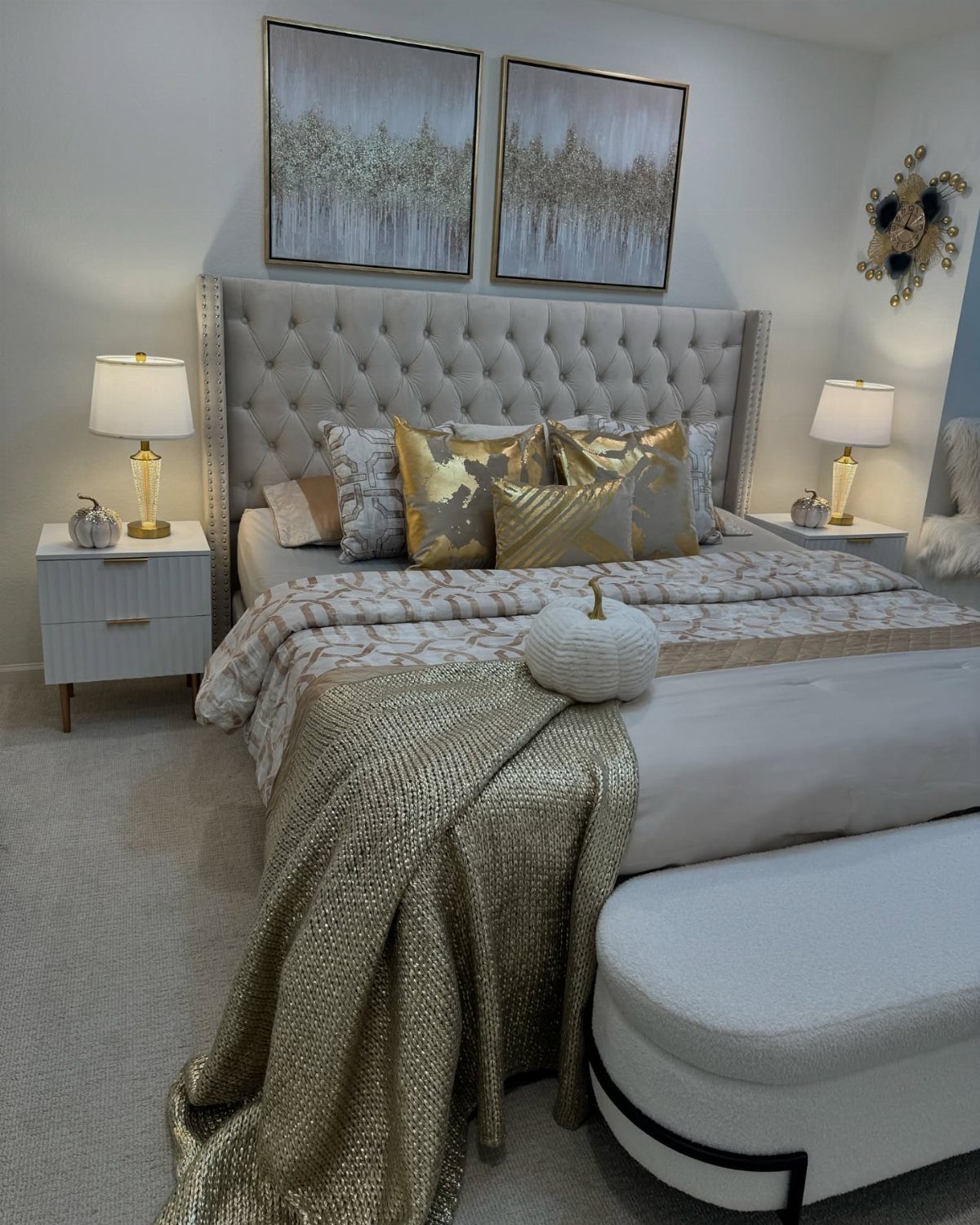 Luxury bedroom with gold lamps, tufted grey headboard, and gold accent bedding.