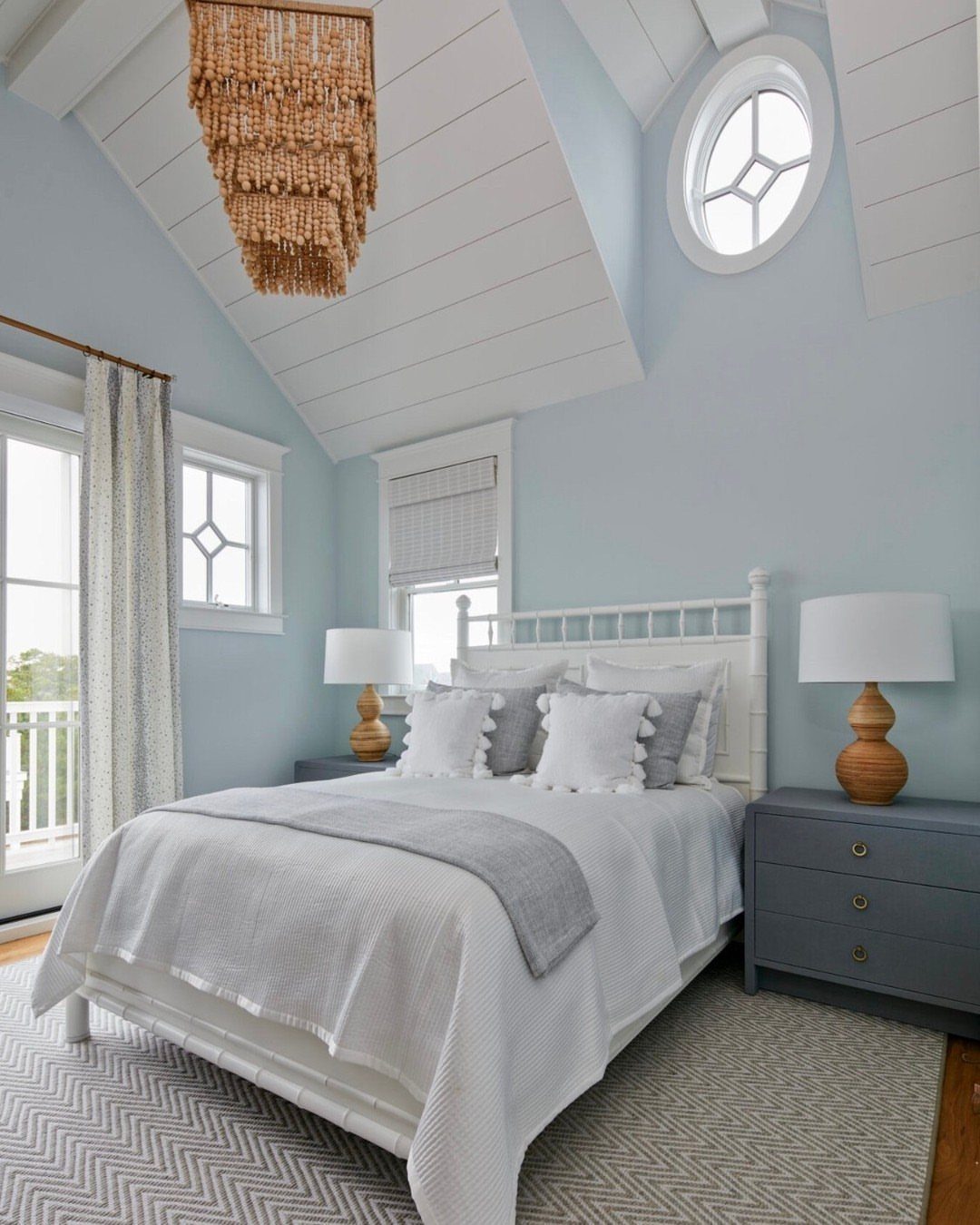 Light blue-gray bedroom walls with a white bed and beaded ceiling chandelier.