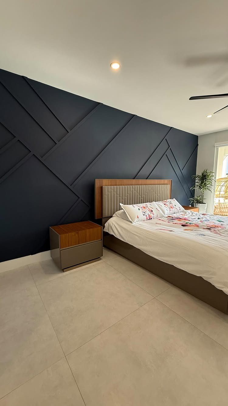 Dark navy blue geometric accent wall in a modern bedroom with white bedding.
