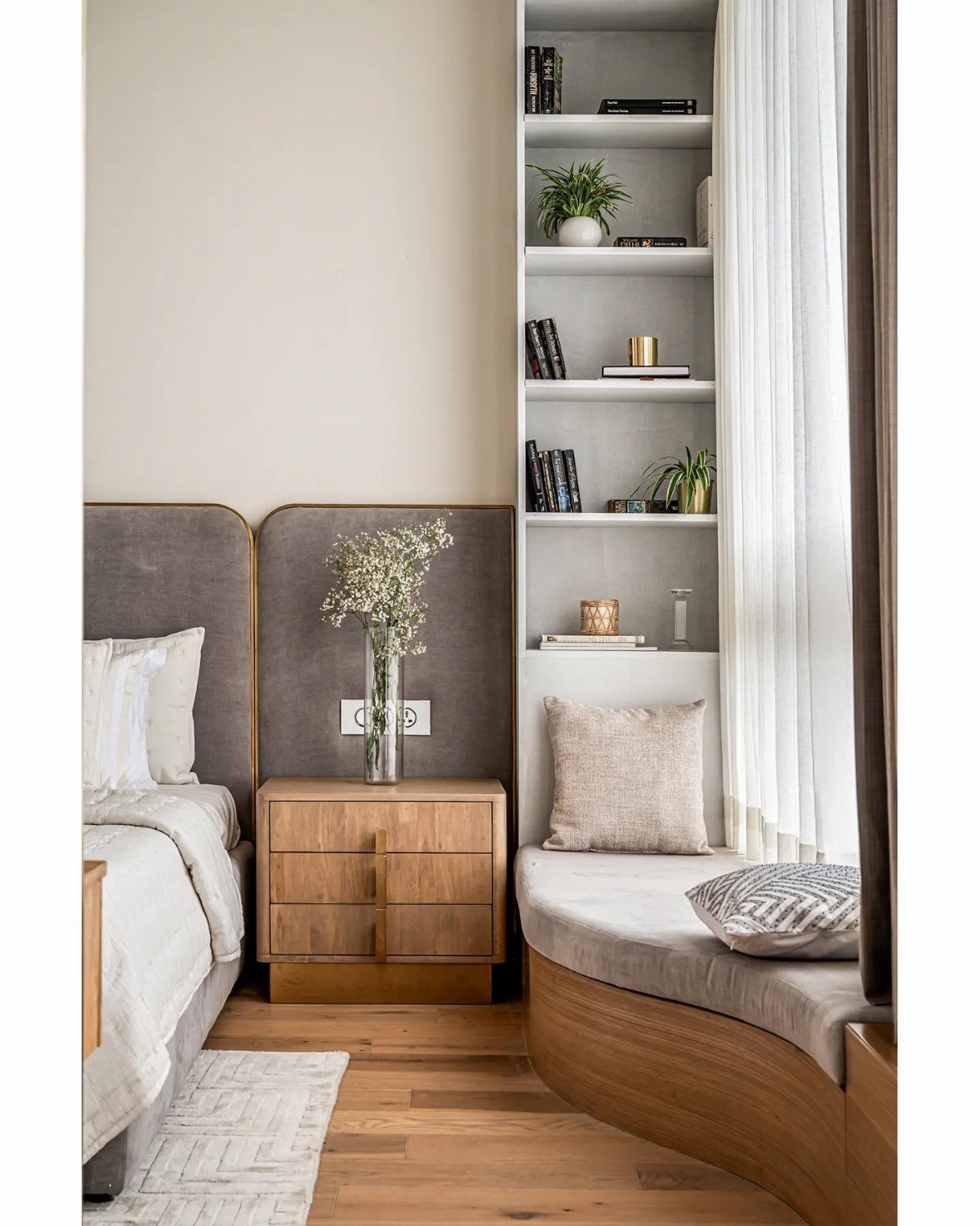 Curved wooden window seat with grey cushions in a modern, light-filled bedroom.