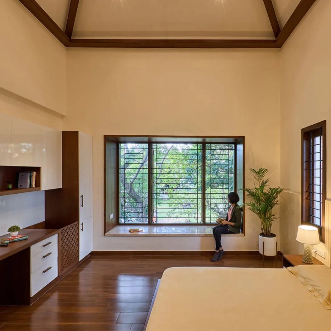Person sitting on a bare bay window ledge in a minimalist bedroom