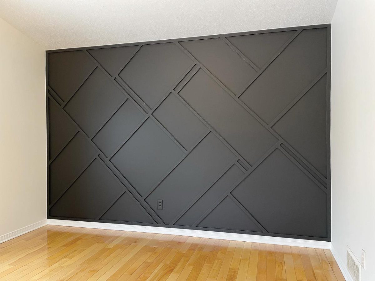 Black accent wall with raised geometric wooden slats in a bright room