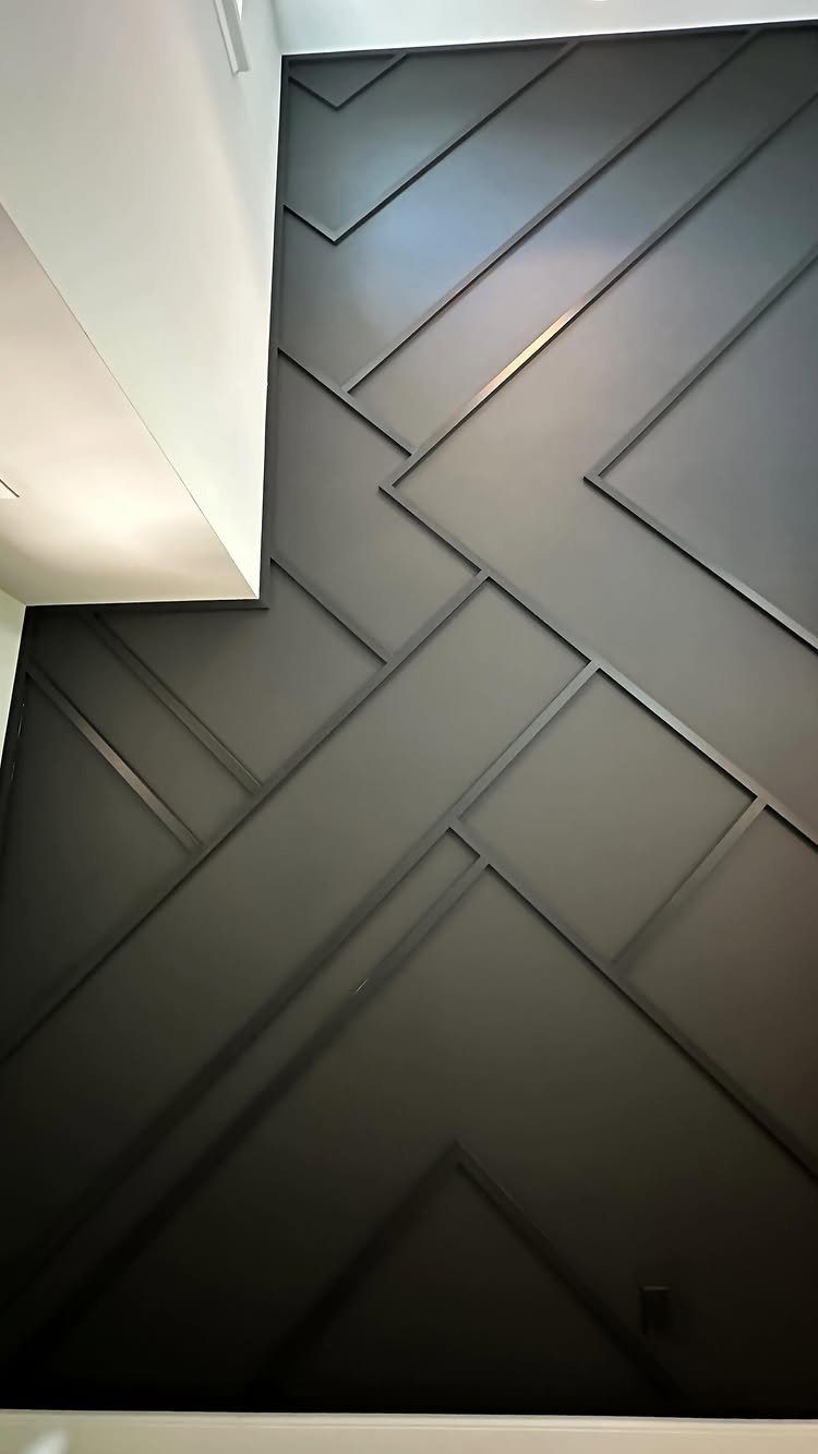 Black accent wall with raised geometric wooden slats creating a textured pattern