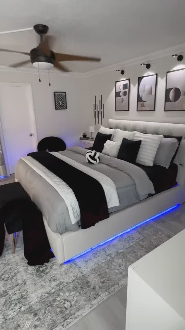Modern bedroom with grey and black bedding and blue LED under-bed lighting.