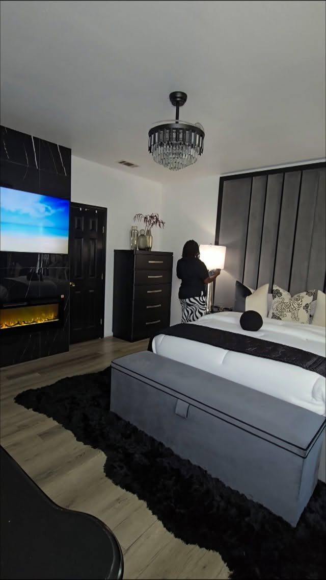 Charcoal grey velvet headboard in a modern black and grey bedroom with chandelier