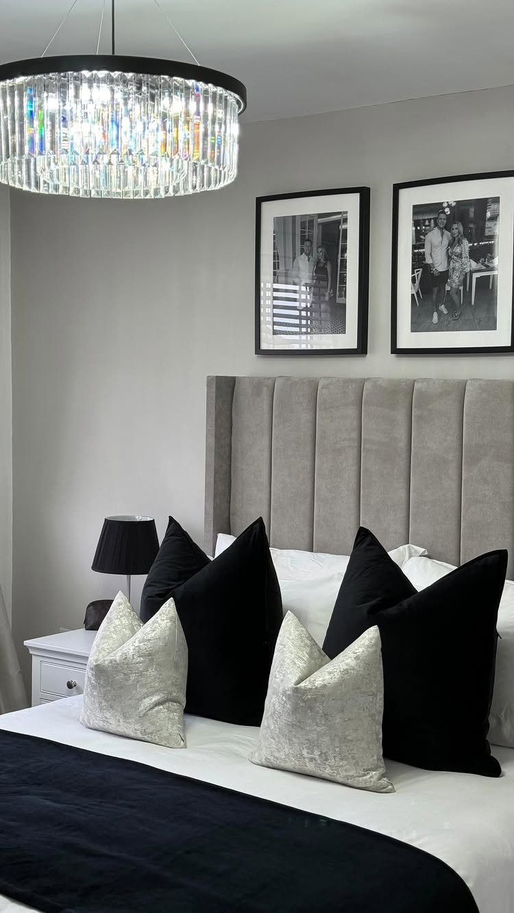 Bedroom with grey fluted headboard, black and silver pillows, and crystal chandelier.