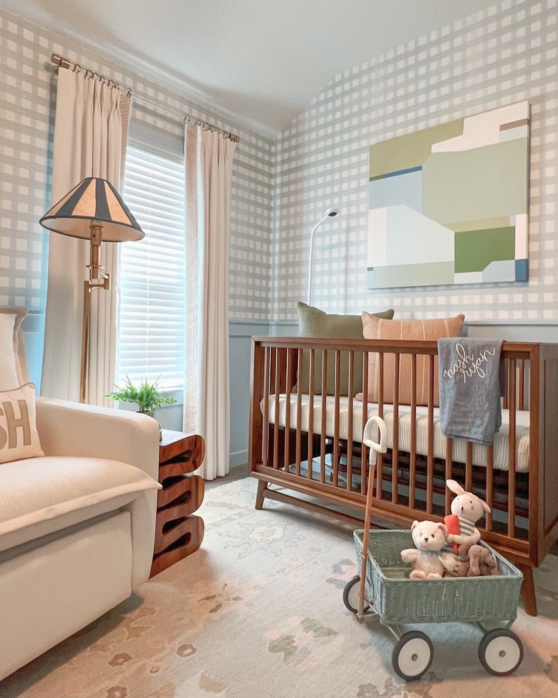 Nursery room with blue and green accents, wooden crib, and checkered wallpaper.