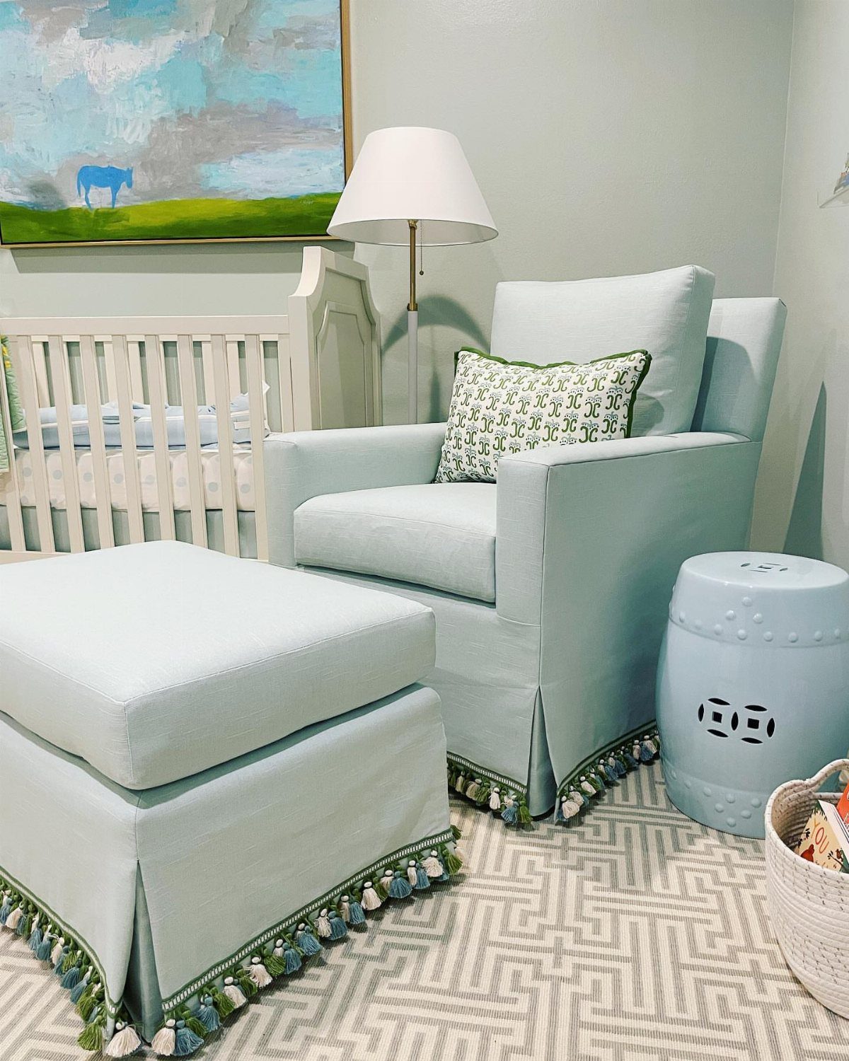 Light blue armchair and ottoman with green accents in a bright nursery room.