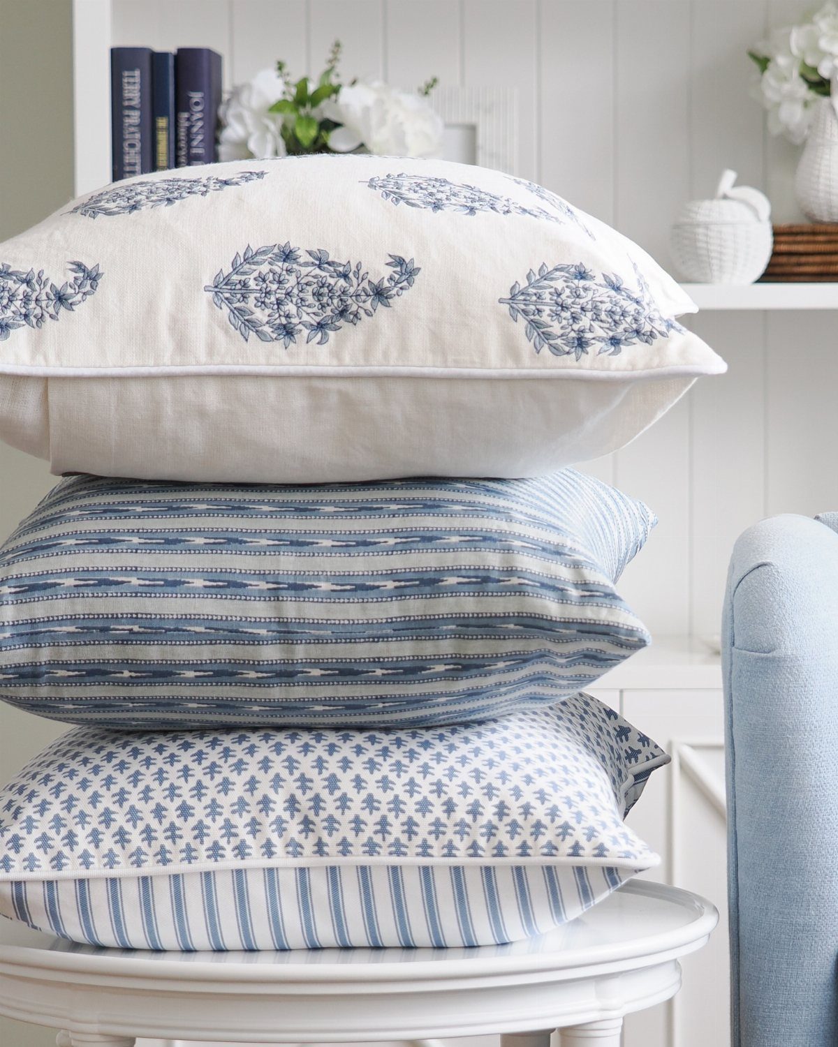 Stack of blue and white patterned throw pillows on a white round table.