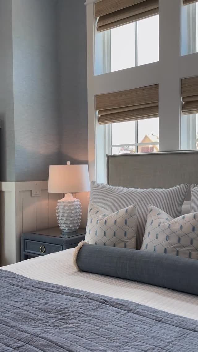 Bed with blue quilted coverlet and patterned pillows in a light blue bedroom