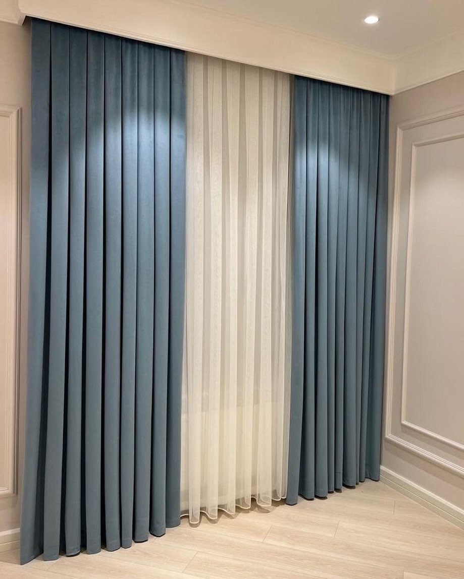 Blue and white floor-to-ceiling curtains hanging against a light-colored wall and floor.