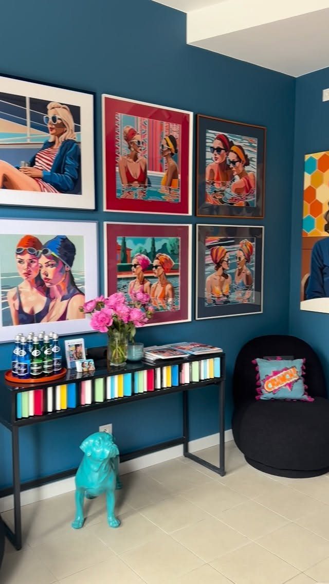Six colorful pop-art portraits hanging on a dark blue wall above a console table.