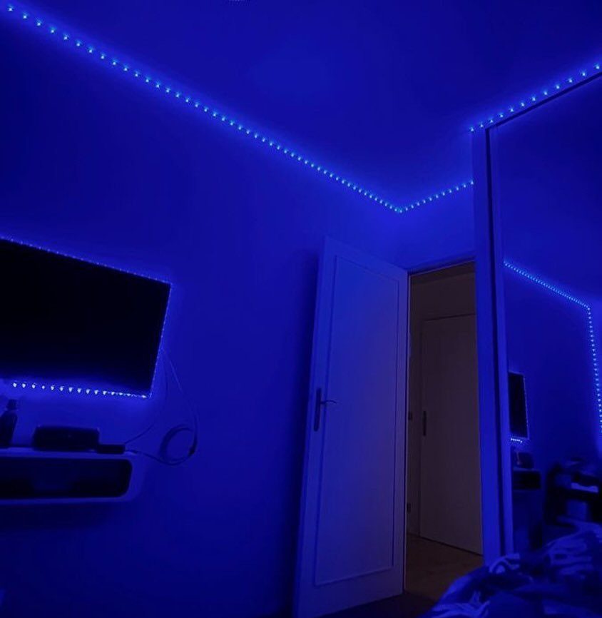 Blue LED strip lights illuminating a room with a television and mirror.