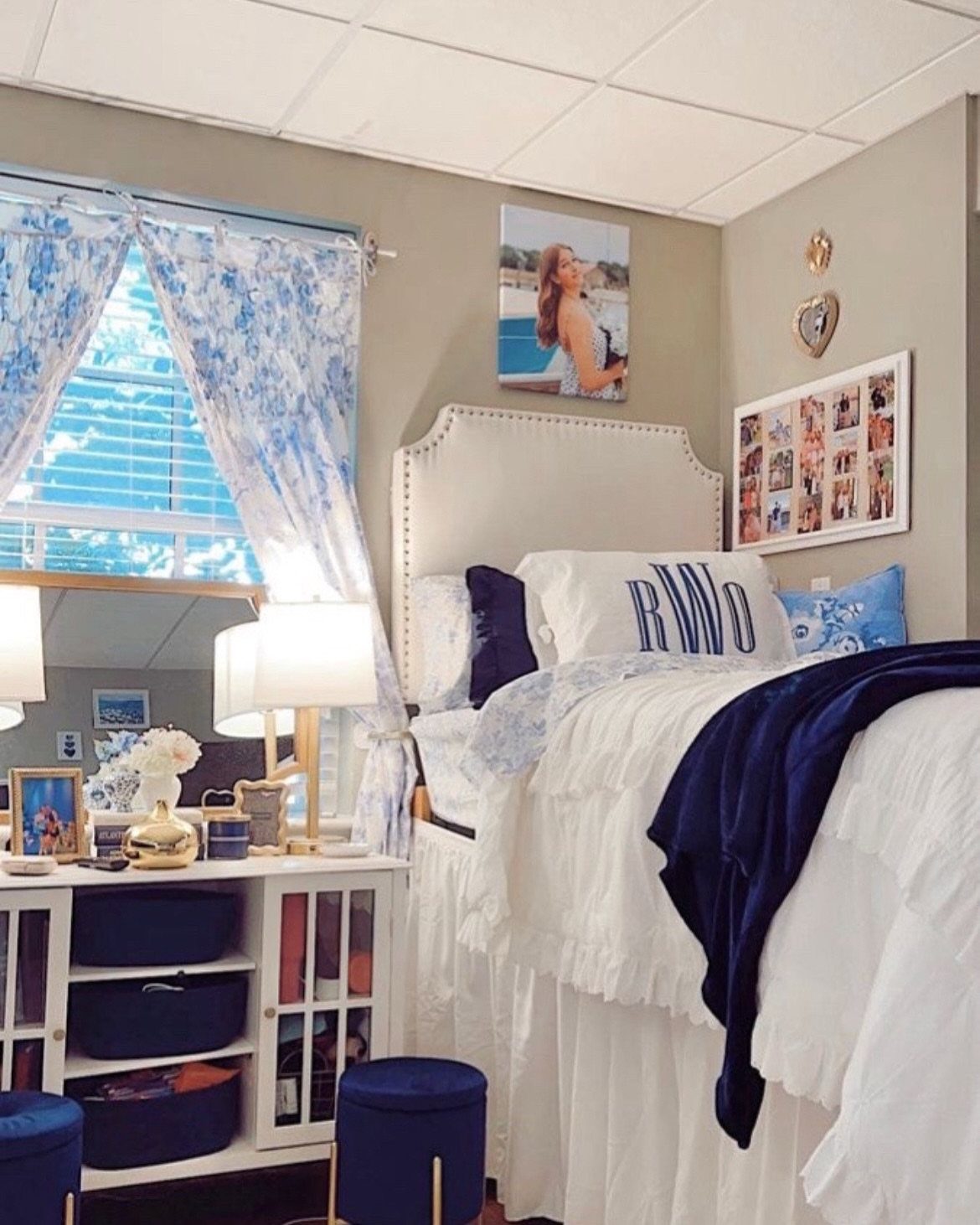 Bedroom with white bedding, navy blue accents, and blue and white curtains.