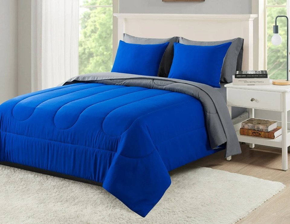 Bed with bright blue comforter and pillows in a bright white bedroom