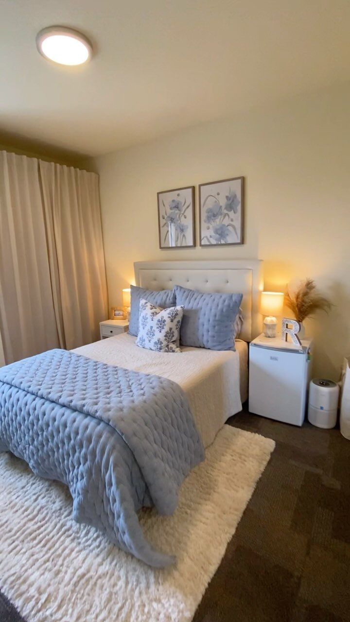 Single bed with light blue bedding and floral art in a small bedroom