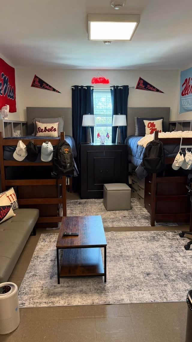 Dorm room with navy blue curtains, bedding, and dark wood furniture and accents.